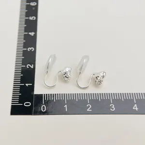 Detail view of silver non-pierced clip-on earrings with soft silicone pads measured on ruler.