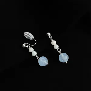 Detailed shot of clip-on earrings with silver chain, white beads, and blue gemstone accents.