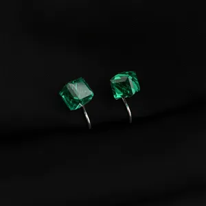 Orecchini a clip in cristallo cubico verde, dettaglio con pietra sfaccettata e finitura argento.