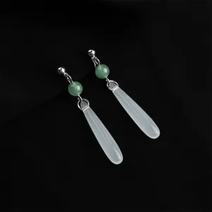 Detailed close-up view of elegant long dangling earrings featuring green and white stones.