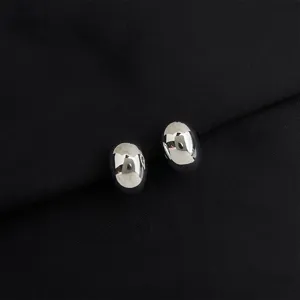 Silver oval metallic stud earrings detail view, polished mirror finish jewelry accessory.