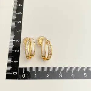 Detailaufnahme vergoldeter zweilagiger Clip-Ohrringe mit weißer Einlage und Zirkoniasteinen.