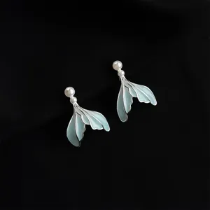 Exquisite detail shot of minimalist mint blue fish tail earrings with delicate pearl accents.