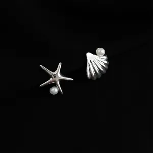 Close-up detail of silver starfish and seashell earrings with pearl embellishment.