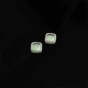 Detail shot of elegant square green cat eye stone stud earrings with polished metal border.