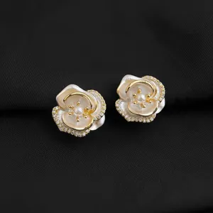 Elegante weiße Kamelien-Ohrclips mit glitzernden Kristallen und Perle im Zentrum detail.