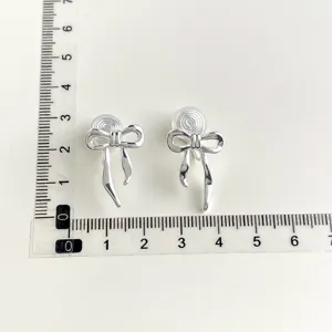 Silver bow clip-on earrings with invisible comfort pads, elegant detail view showing size.