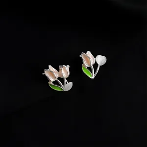 Detail shot of tulip clip-on earrings with pink enamel and pearl accent on black background.