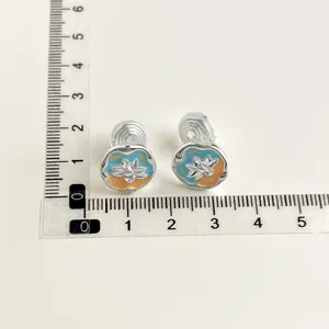 Detail view of non-pierced double-layer clip-on earrings with colorful enamel floral design.