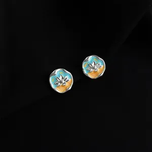 Close-up detail of double-layer flower enamel clip-on earrings with vibrant blue and yellow.