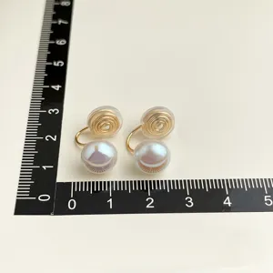 Elegante Ohrclips mit weißen Perlen und goldenen Spiralfassungen für ungestochene Ohren.