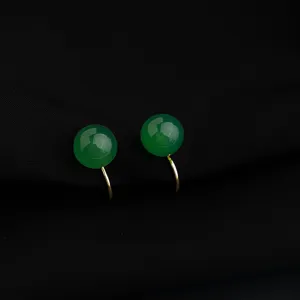 Dettaglio degli orecchini clip con perla verde, pietra liscia e pregiata finitura in metallo dorato.
