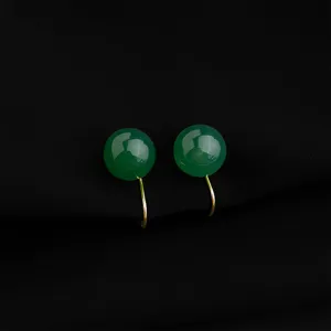 Primo piano dettagliato di eleganti orecchini clip cabochon in pietra verde con base oro.