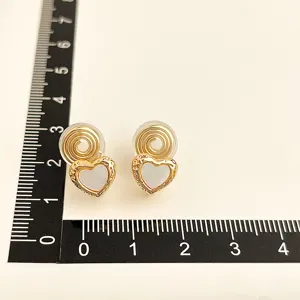 Detailaufnahme vergoldeter Ohrclips mit weißer Herz-Einlage und praktischer Spulenform.