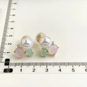 Vista di dettaglio degli eleganti orecchini a clip con perle e pietre rosa e verdi.