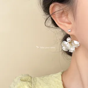 Close up detail of elegant white petal pearl drop earrings, sweet floral jewelry for women.