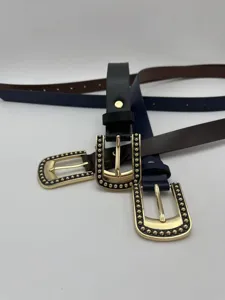 Primer plano detallado de finos cinturones de cuero para mujer con elegantes hebillas doradas.