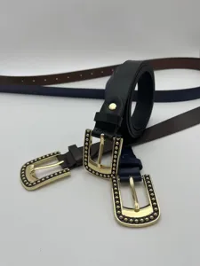 Detalle de primer plano de cinturón fino de mujer con elegante hebilla dorada tachonada.