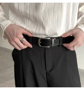 Close-up detail shot of a classic black leather belt with a sleek silver pin buckle.