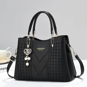Detailed view of the black leather handbag, featuring woven texture, gold hardware and pearl.