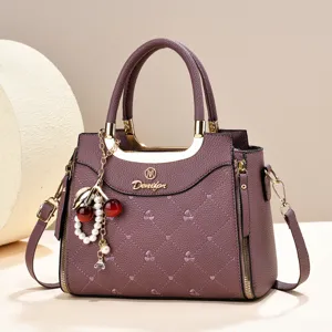 Elegant purple quilted leather handbag featuring a stylish cherry and pearl pendant accessory.