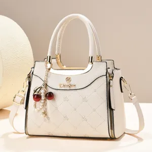 Elegant cream white top-handle handbag with stylish cherry pearl pendant and gold hardware.