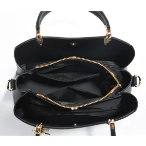Detailed interior view of black leather tote handbag featuring multiple gold zipper compartments.