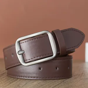 Détail de ceinture en cuir marron avec boucle carrée argentée mate. Accessorio de mode chic.