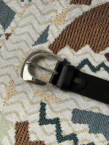 Detailopname van de metalen western gesp met doorn en de zwarte kunstlederen riemband.