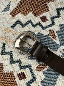 Gedetailleerde close-up van een bruine casual riem met een glinsterende strass gesp.
