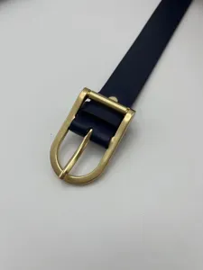 Close-up detail shot of women's slim navy blue belt featuring a sleek gold metal pin buckle.