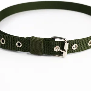 Gros plan détaillé de la ceinture en toile verte avec œillets métalliques et boucle ardillon.