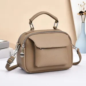 Brown leather crossbody handbag with top handle, front flap pocket and metal hardware.