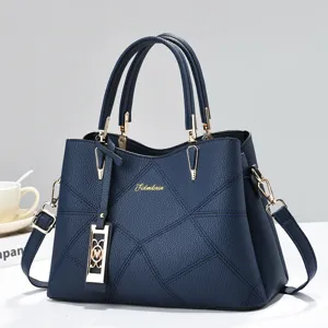 Dark blue textured leather handbag detailed view with chic geometric design and gold hardware.