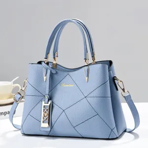 Detailed view of light blue leather tote bag, geometric pattern stitching and gold hardware.