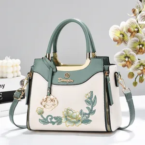 Embroidery handbag detail shot showcasing exquisite stitching and dual-tone green and off-white design.