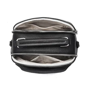 Multi-compartment interior detail view of black leather handbag with smooth zippers.