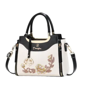 Elegant black and white embroidered women handbag with top handle and adjustable strap.
