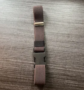 Gros plan d'une ceinture élastique marron avec boucle plastique et fermoir métallique.