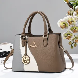 Color block handbag detail, soft leather shoulder bag with double handles and metal hardware charm.