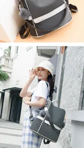 Dark grey canvas backpack detail showcasing white contrast trim and cute furry pom-pom charm.