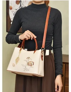 Elegant women's PU leather crossbody bag with vintage floral embroidery and leaf charm.