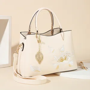 Elegant cream women handbag with chic floral embroidery, top handle and crossbody strap.