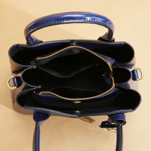 Vista dettagliata dell'interno di una borsa tote in pelle verniciata blu con scomparti multipli.