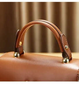 Close-up detail van bruine leren dames handvat tas met gouden klinknagels en beslag.