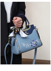 Close-up detail of blue gradient women handbag with peony embroidery and stylish silk scarf.