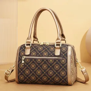Close-up detail of vintage brown barrel handbag with gold handles and monogram print pattern.
