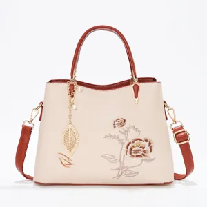 Elegant women handbag with floral embroidery, top handle and crossbody strap, chic design.