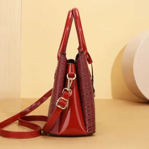 Dettaglio borsa tote in pelle verniciata rossa, vista laterale borsa a spalla cocco con dettagli oro.
