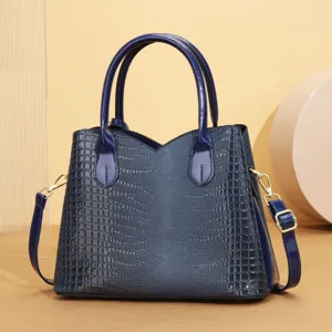 Dettaglio della borsa a mano in pelle goffrata blu con texture lucida e dettagli dorati raffinati.